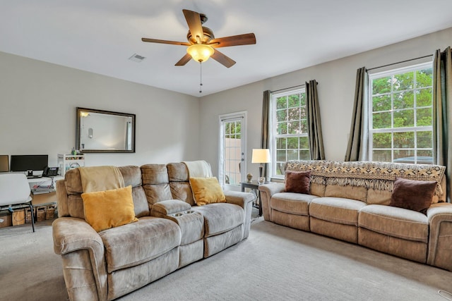 living room with a ceiling fan, light colored carpet, and visible vents