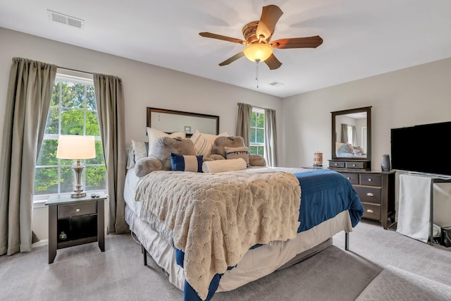 bedroom featuring visible vents, light colored carpet, and a ceiling fan