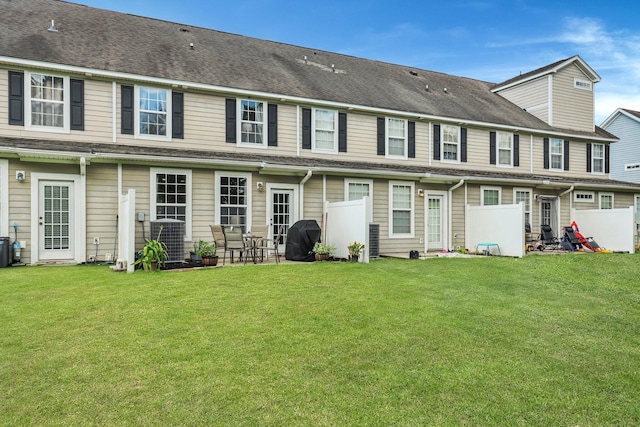 back of property with a yard, fence, and central AC