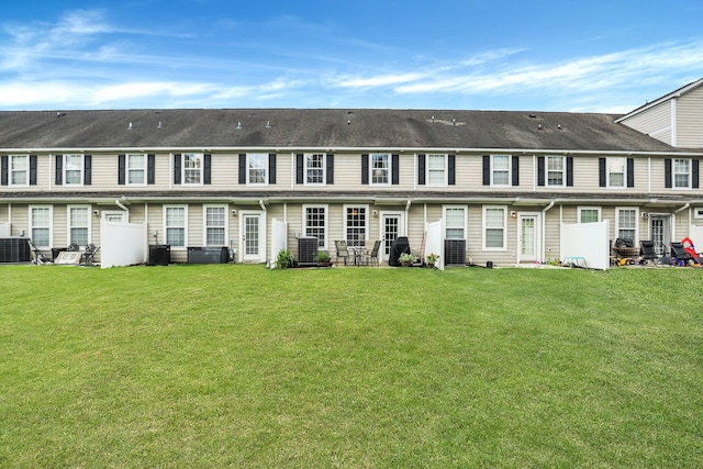 rear view of property featuring central air condition unit and a lawn