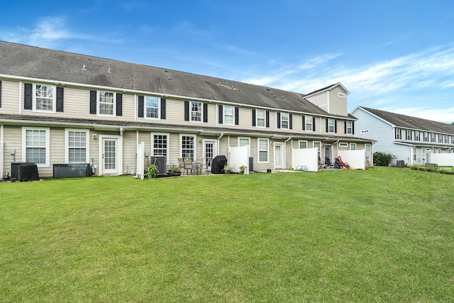 rear view of house with a lawn and cooling unit