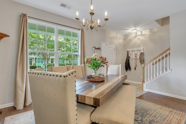 dining room featuring visible vents, an inviting chandelier, wood finished floors, and stairs