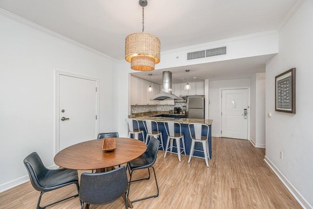 dining space with light hardwood / wood-style flooring and ornamental molding