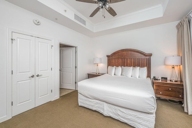 bedroom with ceiling fan, a raised ceiling, carpet floors, and a closet