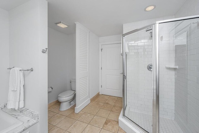 bathroom featuring tile patterned flooring, toilet, and a shower with door