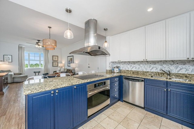 kitchen with ceiling fan, hanging light fixtures, blue cabinets, island range hood, and appliances with stainless steel finishes