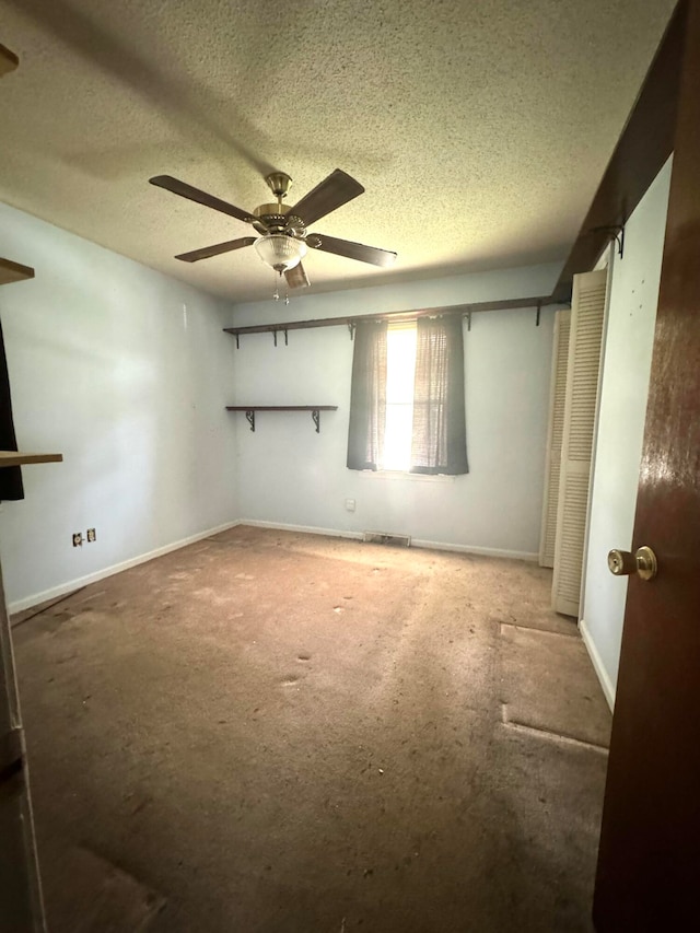 empty room with ceiling fan and a textured ceiling