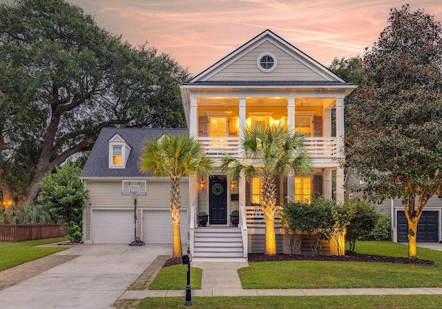 greek revival inspired property with a garage, a lawn, and a balcony