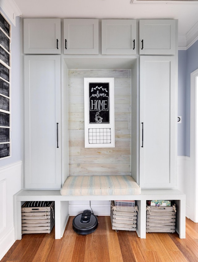 mudroom with crown molding, wood walls, and light hardwood / wood-style floors