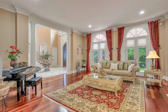 living room with hardwood / wood-style floors, decorative columns, and crown molding