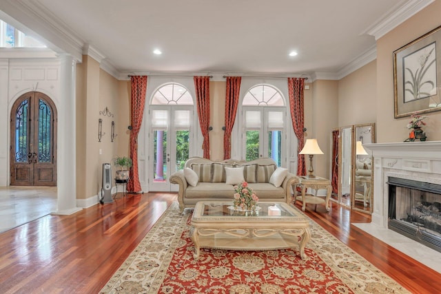 living room featuring hardwood / wood-style flooring, ornamental molding, french doors, and decorative columns