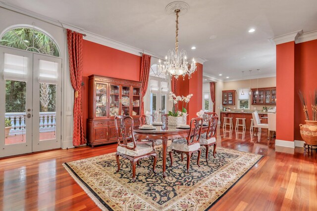 dining room with hardwood / wood-style flooring, a chandelier, crown molding, and french doors