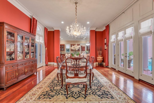 dining space with hardwood / wood-style flooring, an inviting chandelier, and ornamental molding