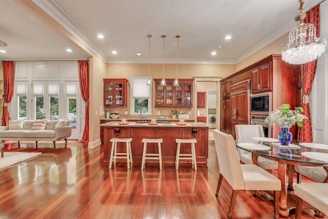 kitchen with built in appliances, an inviting chandelier, dark hardwood / wood-style flooring, crown molding, and light stone counters