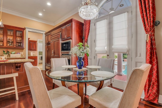 dining area with washer / clothes dryer, dark wood-type flooring, an inviting chandelier, and crown molding