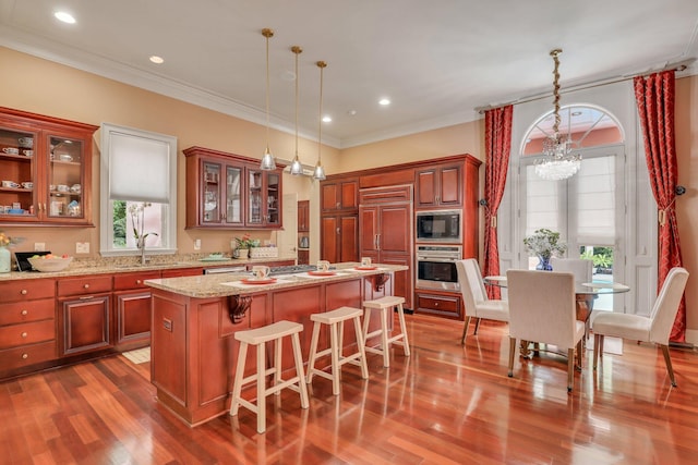 kitchen with built in appliances, a kitchen island, an inviting chandelier, dark wood-type flooring, and ornamental molding