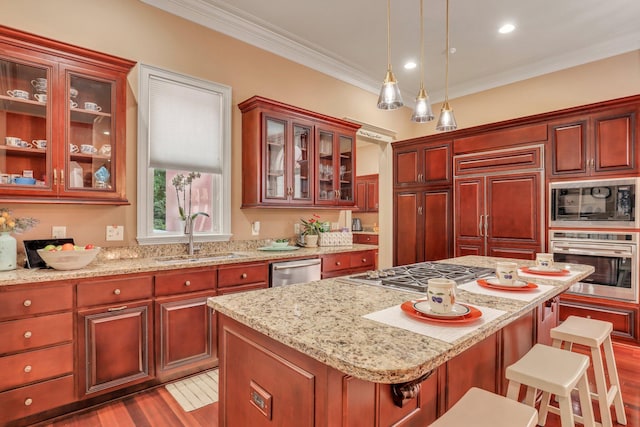 kitchen featuring built in appliances, decorative light fixtures, a center island, sink, and a breakfast bar area