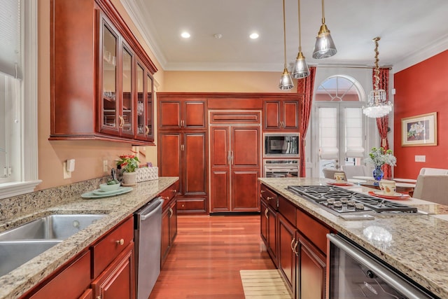 kitchen featuring crown molding, built in appliances, light hardwood / wood-style flooring, and light stone countertops