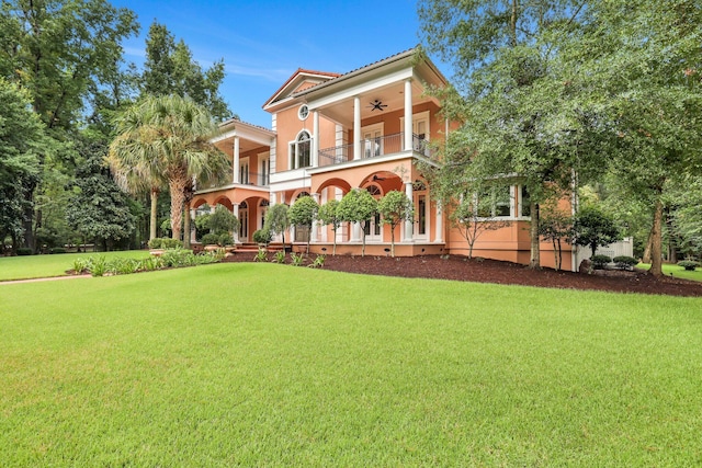 back of property featuring a lawn, ceiling fan, and a balcony