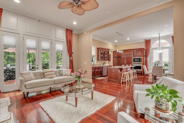 living room with ceiling fan with notable chandelier, crown molding, and wood-type flooring