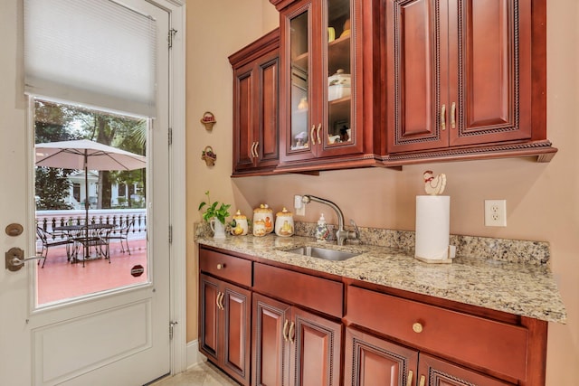 kitchen featuring plenty of natural light, light stone counters, and sink