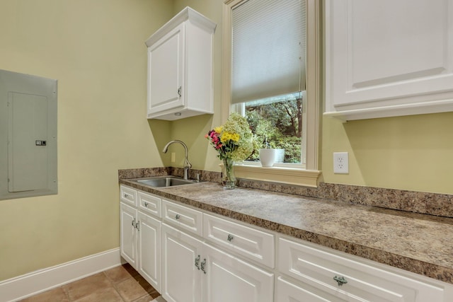 kitchen with white cabinets, electric panel, light tile patterned floors, and sink