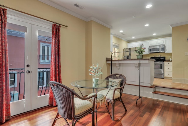 dining room featuring light hardwood / wood-style floors, crown molding, and french doors