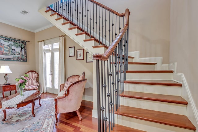 stairway with wood-type flooring, crown molding, and french doors