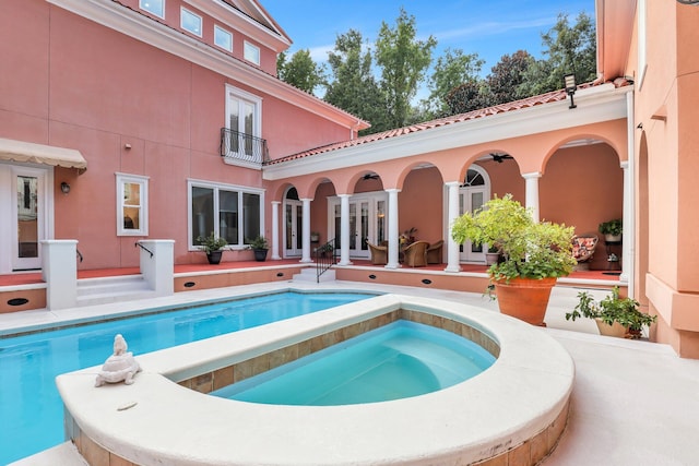 view of pool with french doors and an in ground hot tub