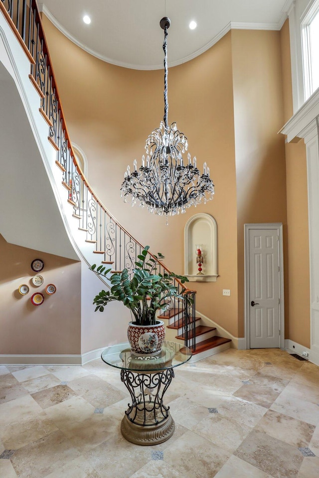 foyer with a high ceiling, ornamental molding, and a chandelier