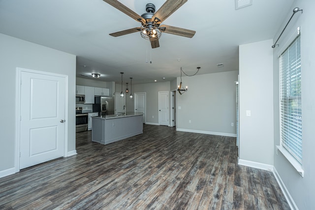 unfurnished living room featuring ceiling fan with notable chandelier, dark hardwood / wood-style flooring, and sink