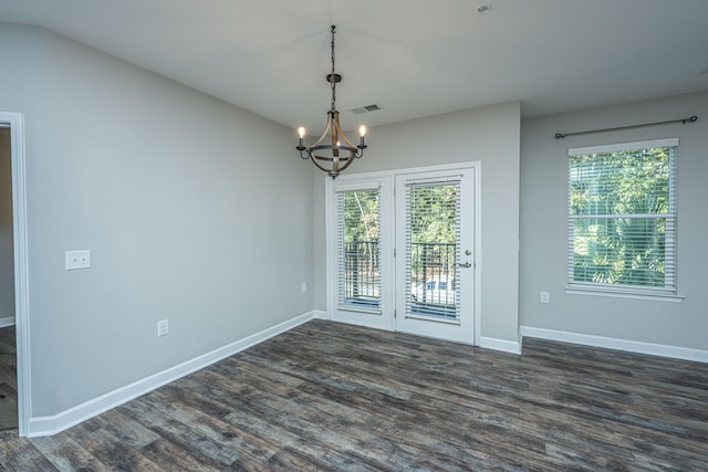 empty room featuring an inviting chandelier and dark wood-type flooring