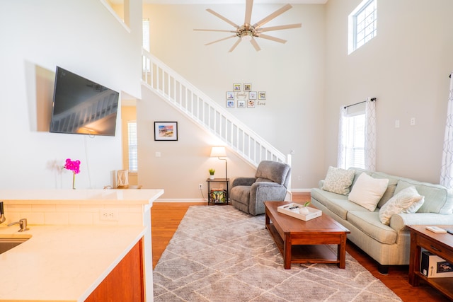 living room featuring hardwood / wood-style flooring, a towering ceiling, and ceiling fan