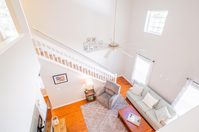 living room with ceiling fan, hardwood / wood-style flooring, and a towering ceiling