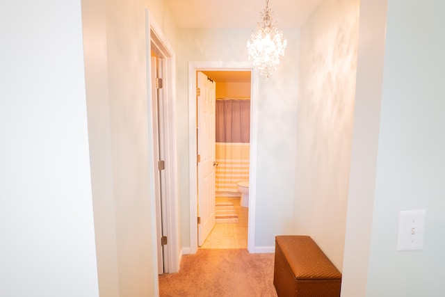 hallway with a notable chandelier and light colored carpet