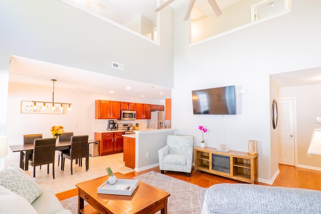 living room featuring a high ceiling, light hardwood / wood-style flooring, and a chandelier