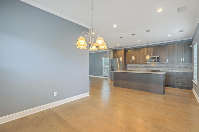 kitchen featuring tasteful backsplash, hanging light fixtures, appliances with stainless steel finishes, and light hardwood / wood-style flooring