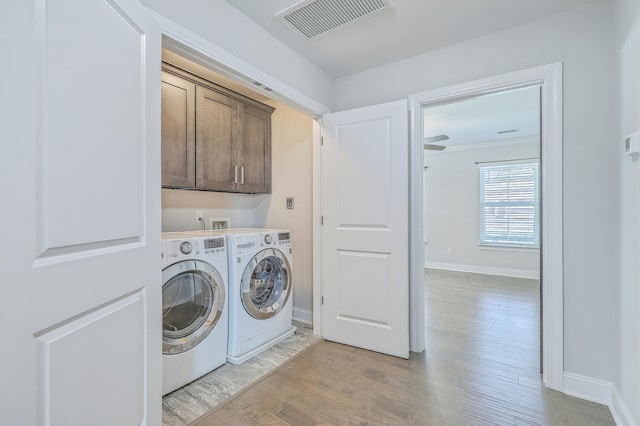 laundry room with ornamental molding, light hardwood / wood-style flooring, cabinets, and washing machine and clothes dryer