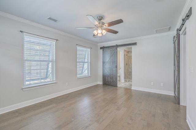 unfurnished room featuring a barn door, ceiling fan, plenty of natural light, and light wood-type flooring