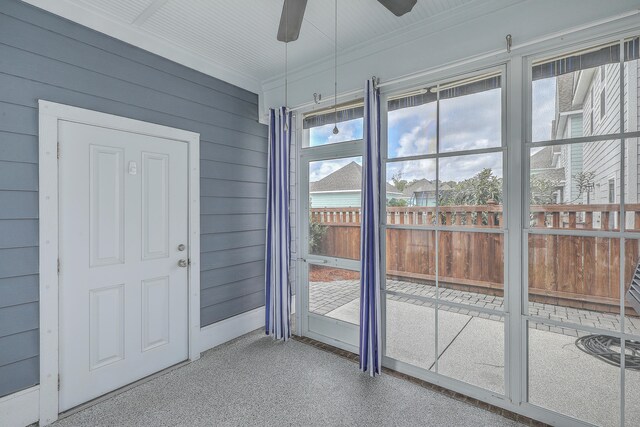 entryway with wood walls, ceiling fan, a healthy amount of sunlight, and ornamental molding