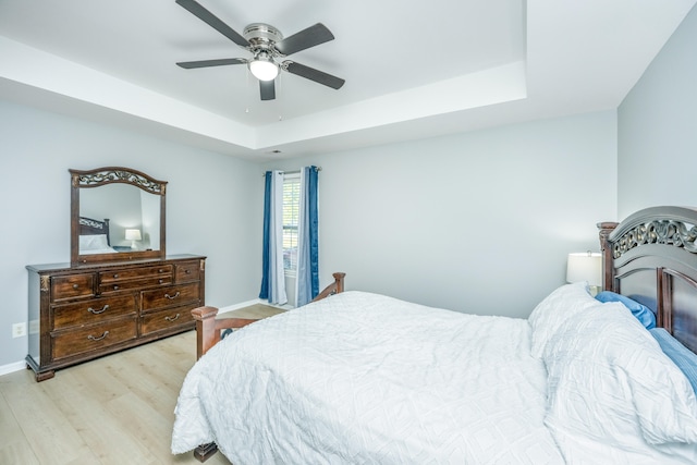 bedroom featuring light hardwood / wood-style floors, a raised ceiling, and ceiling fan