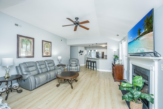 living room with light hardwood / wood-style floors, ceiling fan, and vaulted ceiling