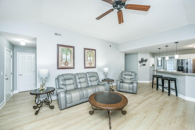 living room featuring ceiling fan, light wood-type flooring, and vaulted ceiling