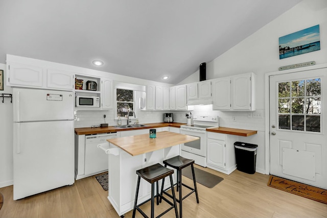 kitchen with lofted ceiling, white appliances, white cabinetry, wood counters, and a sink