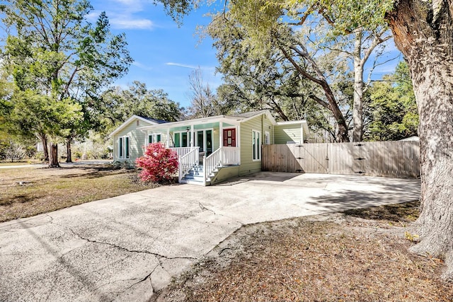 view of front facade with covered porch, driveway, and a gate