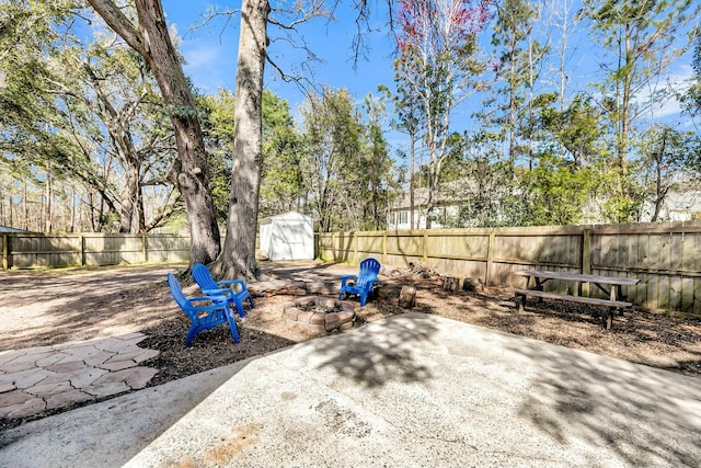 view of patio / terrace with an outdoor fire pit, an outdoor structure, a storage shed, and a fenced backyard