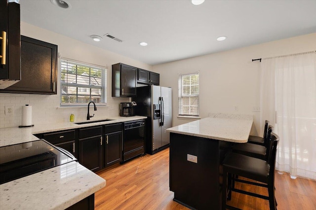 312 Kelsey Blvd, Wando, SC 29492 - kitchen featuring dishwasher, stainless steel refrigerator with ice dispenser, tasteful backsplash, light wood-style flooring, and a kitchen bar