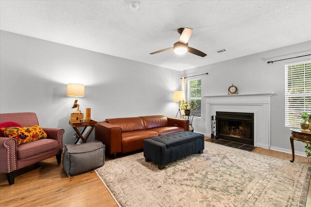 living area featuring visible vents, wood finished floors, a textured ceiling, and ceiling fan