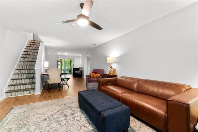 living room with ceiling fan, baseboards, wood finished floors, and stairway