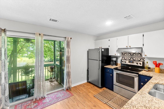 kitchen featuring a textured ceiling, light wood-type flooring, appliances with stainless steel finishes, white cabinets, and under cabinet range hood